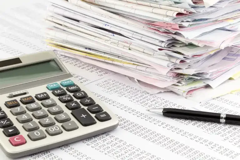 Calculator and a stack of invoices illustrating the importance of scalability in invoice automation. Data labelling ensures systems can handle high volumes while maintaining accuracy and performance, driving innovation and continuous improvement.