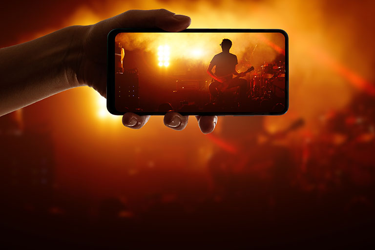 DeeLab, Video labeling, Silhouette of hand using camera phone to take pictures and videos at pop concert, festival.