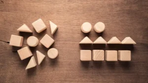 Two groups of wooden blocks: one unorganized and the other organized by shape, representing the process of Supervised Learning in machine learning.