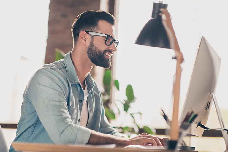 Photo portrait of man working on desktop at table in modern industrial office indoors.