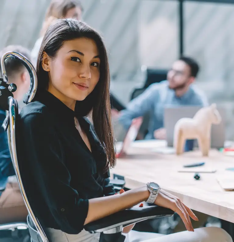 An Asian woman sitting in a meeting room during a business meeting, looking straight at the camera. Join DeeLab today.