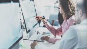 Two colleagues, a woman and a man, intensely studying data displayed on a computer screen, representing DeeLab's expertise in web research and market analysis services.