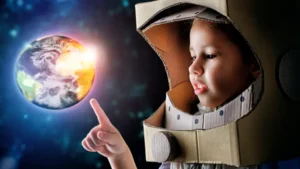 Small boy in a self-made space suit points at an illustration of Earth from space, representing how satellite imagery and data labeling track carbon emissions to guide decisions for a safer, cleaner planet for future generations.