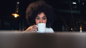 A woman working on her computer while sipping coffee, illustrating a typical day in the life of a data annotator.