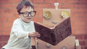 Young boy shows a book to his homemade cardboard robot, symbolizing how AI systems learn from labeled data before processing it to AI data.