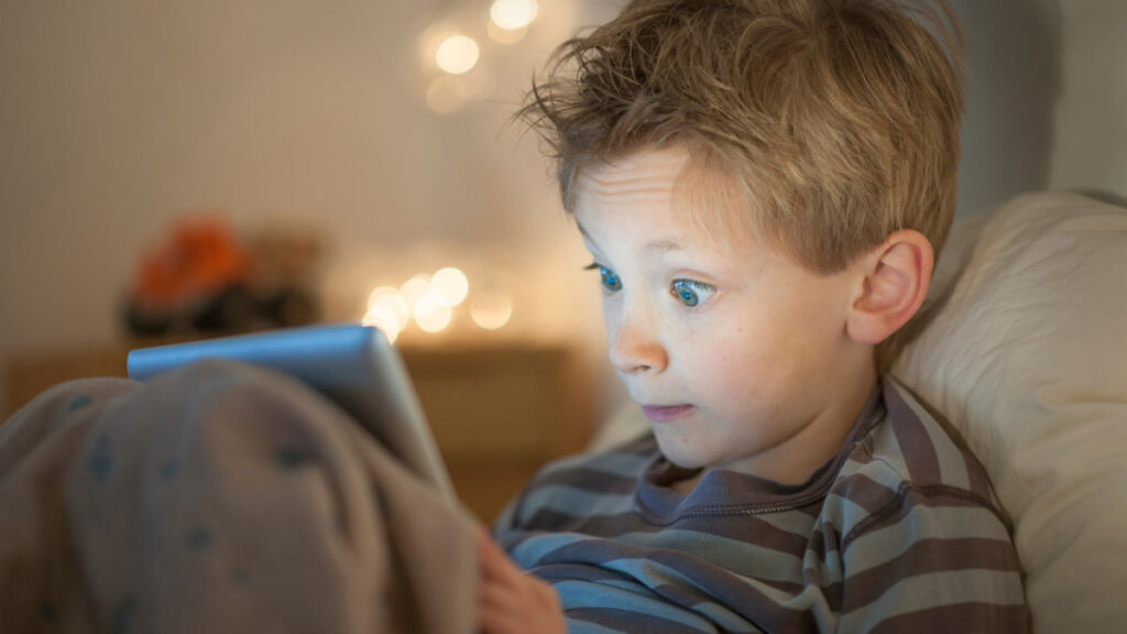 Boy staring intently at a tablet screen, symbolizing the need for safe and responsible content moderation online.